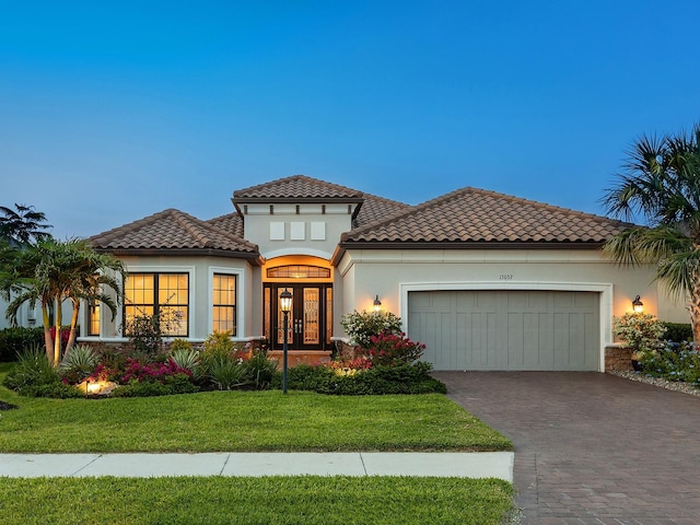 15037 Montello Way, Lakewood Ranch, FL 34211 - mediterranean / spanish home with decorative driveway, an attached garage, stucco siding, french doors, and a front lawn