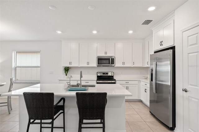 9725 Last Light Gln, Parrish, FL 34219 - kitchen featuring stainless steel appliances, a sink, light tile patterned flooring, light countertops, and an island with sink
