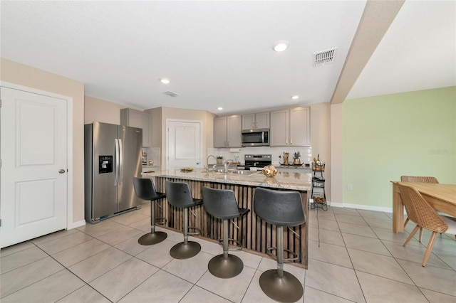 2969 Great Abaco Way, Bradenton, FL 34208 - kitchen featuring stainless steel appliances, gray cabinets, a kitchen bar, a center island with sink, and a sink