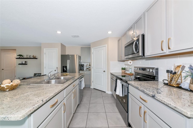 2969 Great Abaco Way, Bradenton, FL 34208 - kitchen featuring appliances with stainless steel finishes, a sink, light tile patterned flooring, backsplash, and a kitchen island with sink