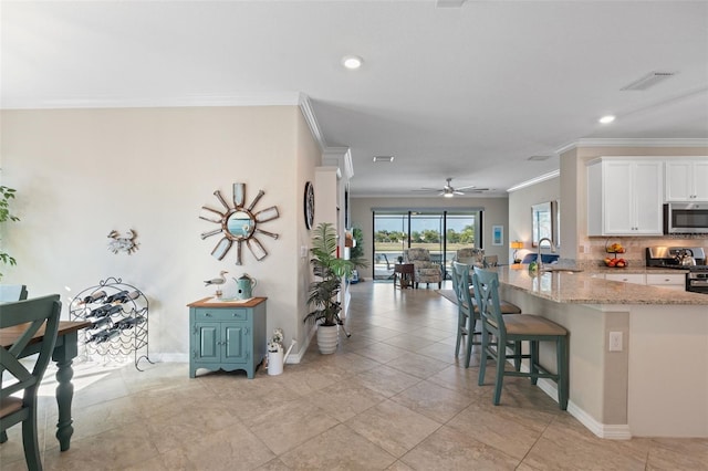 14309 Carolina Sky Pl, Lakewood Ranch, FL 34211 - kitchen featuring a kitchen breakfast bar, a sink, visible vents, stainless steel appliances, and ornamental molding