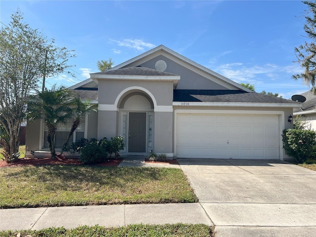 view of front of home with stucco siding, a front lawn, driveway, and a garage