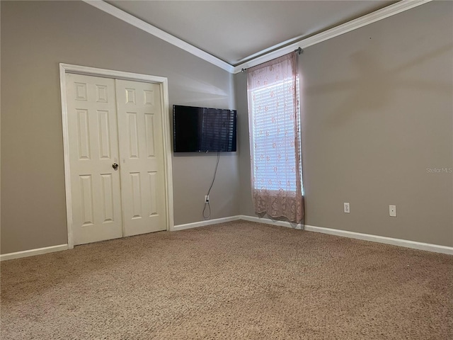 carpeted spare room featuring lofted ceiling, baseboards, and ornamental molding