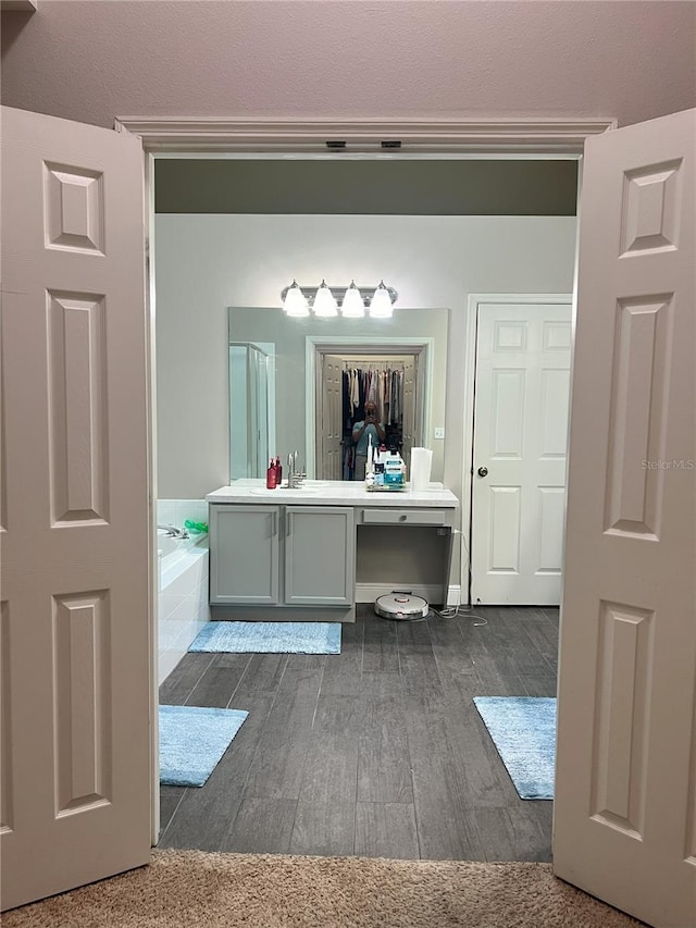 bathroom featuring a bath, wood finished floors, and vanity