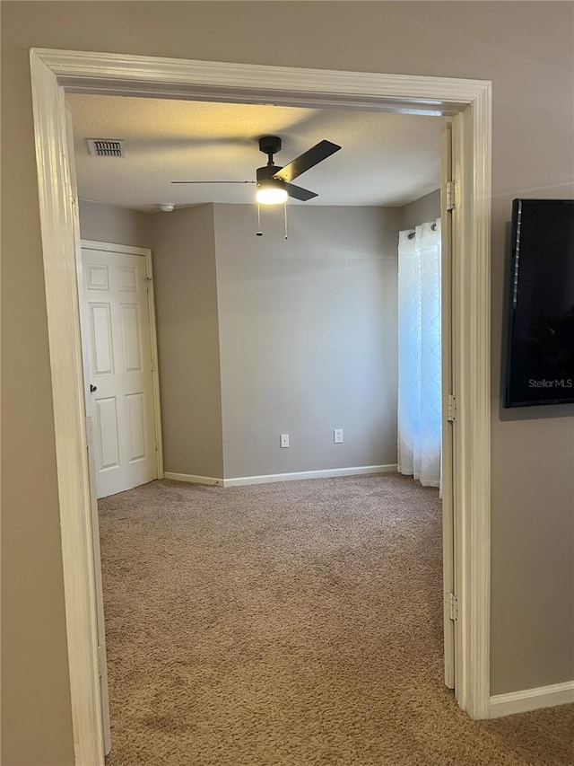 spare room with ceiling fan, baseboards, visible vents, and carpet