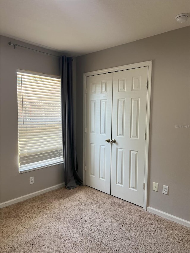 unfurnished bedroom featuring baseboards, carpet, and a closet