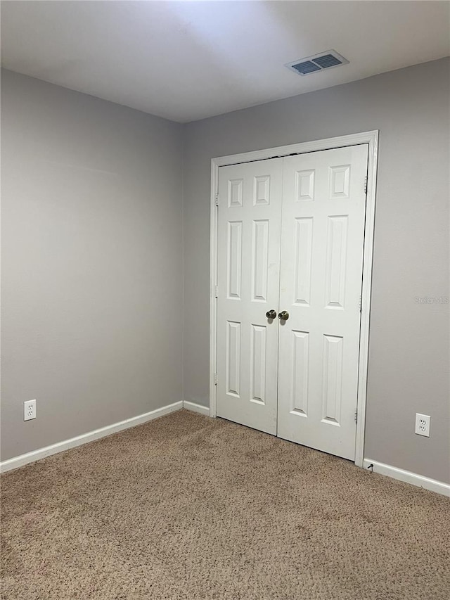 unfurnished bedroom with visible vents, baseboards, carpet floors, and a closet