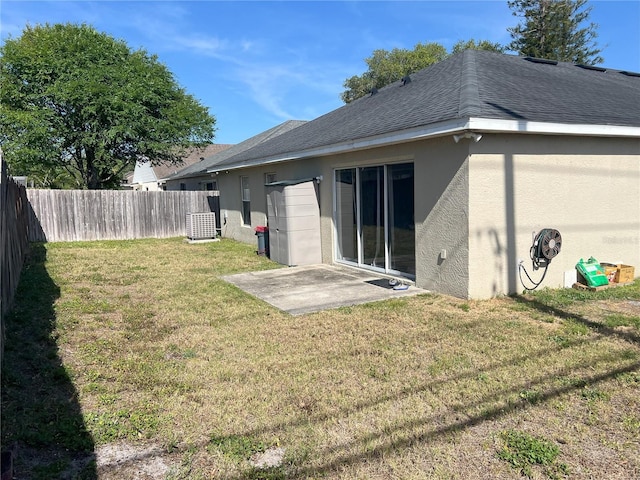 back of house featuring a shingled roof, a fenced backyard, a yard, a patio, and stucco siding
