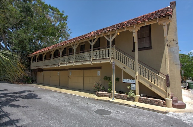 view of front of home featuring a tile roof, stairs, and stucco siding