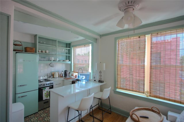 525 Rawls Ave, Sarasota, FL 34236 - kitchen with a ceiling fan, tasteful backsplash, gas stove, light countertops, and a peninsula
