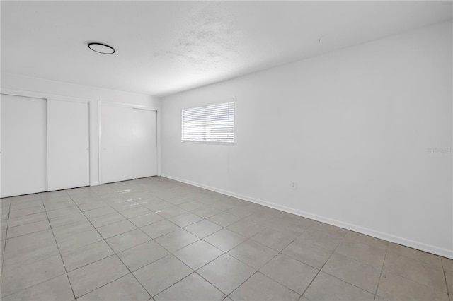 spare room with baseboards and light tile patterned floors