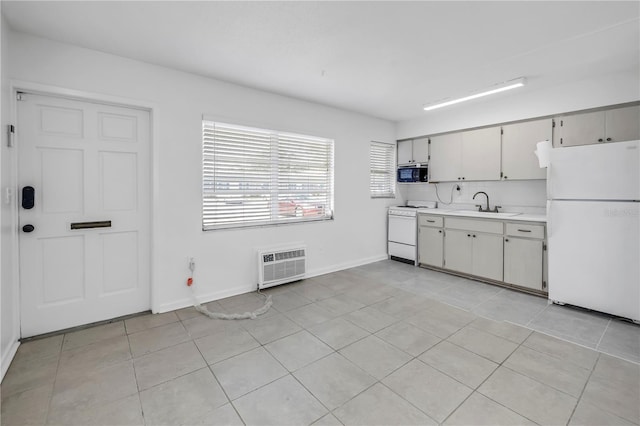 kitchen featuring a sink, white appliances, light tile patterned floors, light countertops, and baseboards