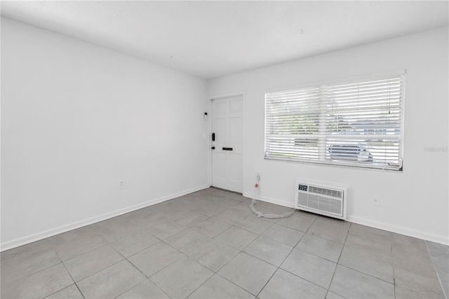unfurnished room with a wall mounted air conditioner, baseboards, and light tile patterned floors