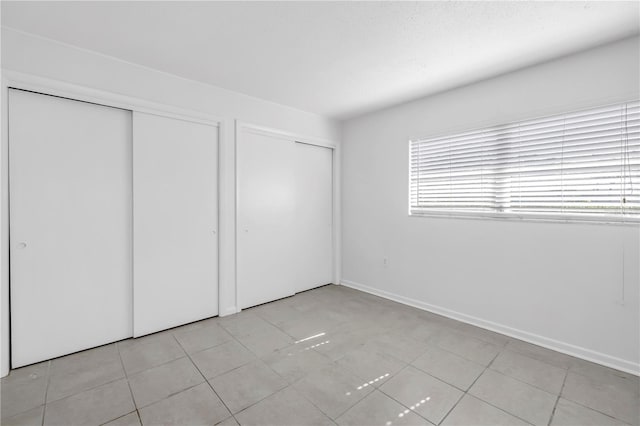 unfurnished bedroom with multiple windows, multiple closets, and light tile patterned floors