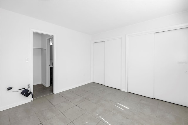 unfurnished bedroom featuring multiple closets and light tile patterned floors