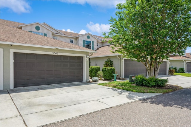 view of front of house featuring a shingled roof, an attached garage, stucco siding, and concrete driveway