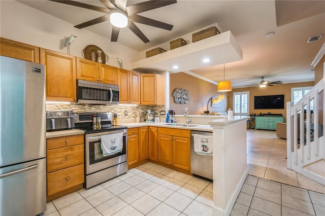 kitchen featuring a sink, open floor plan, tasteful backsplash, a ceiling fan, and appliances with stainless steel finishes