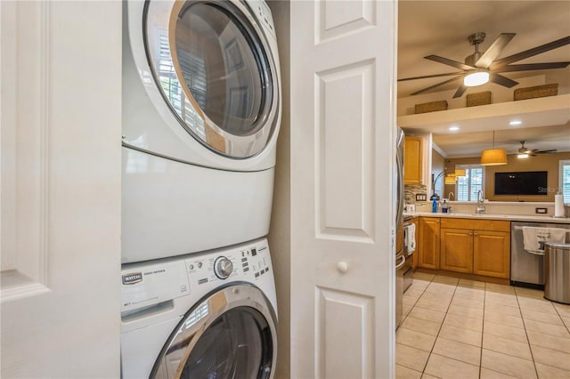 washroom with laundry area, stacked washing maching and dryer, ceiling fan, a sink, and light tile patterned floors
