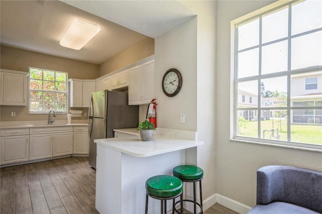 kitchen with light wood-style floors, freestanding refrigerator, white cabinets, and a wealth of natural light