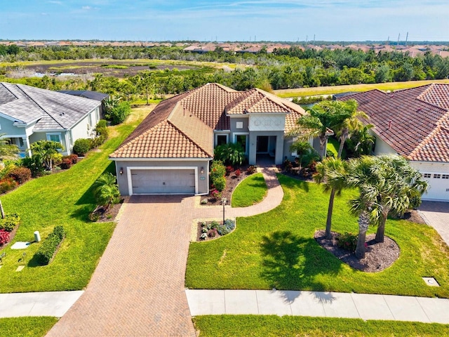 mediterranean / spanish house featuring stucco siding, decorative driveway, a tile roof, and a garage