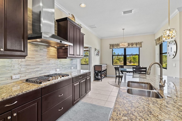 kitchen with wall chimney range hood, decorative backsplash, a sink, ornamental molding, and stainless steel gas cooktop