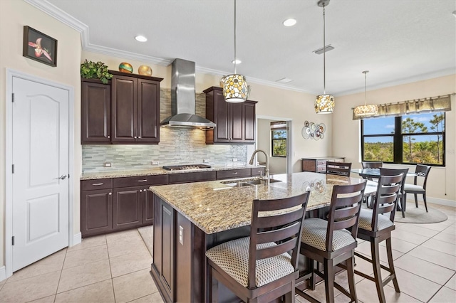 kitchen featuring stainless steel gas cooktop, a sink, light tile patterned floors, tasteful backsplash, and wall chimney range hood