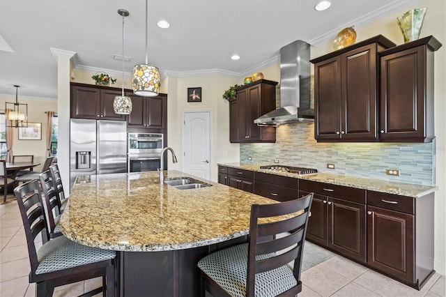 kitchen with light tile patterned floors, appliances with stainless steel finishes, wall chimney range hood, a sink, and a kitchen breakfast bar