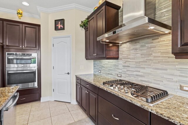 kitchen featuring tasteful backsplash, stainless steel appliances, baseboards, wall chimney exhaust hood, and light tile patterned flooring