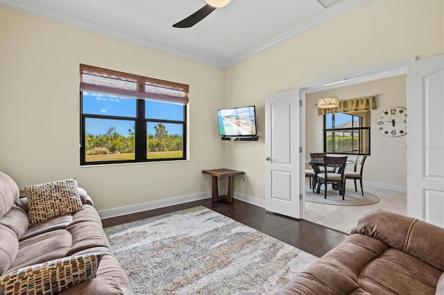 living room featuring baseboards, ornamental molding, ceiling fan, and wood finished floors