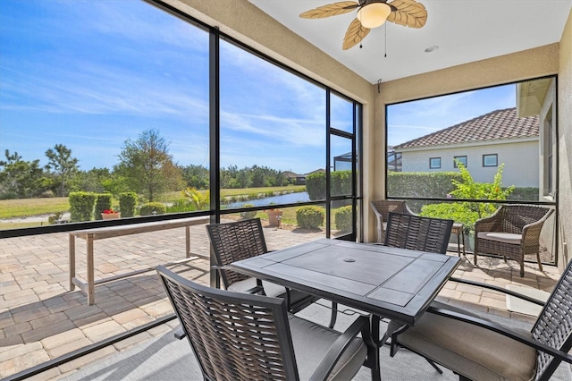 sunroom / solarium featuring a ceiling fan, a water view, and outdoor dining area