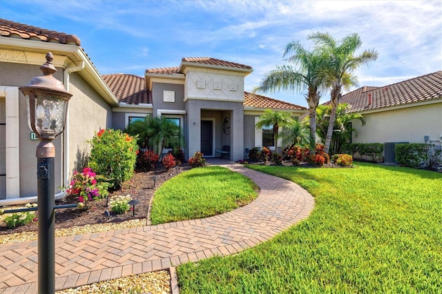 view of front of house with stucco siding, a front yard, and a tiled roof