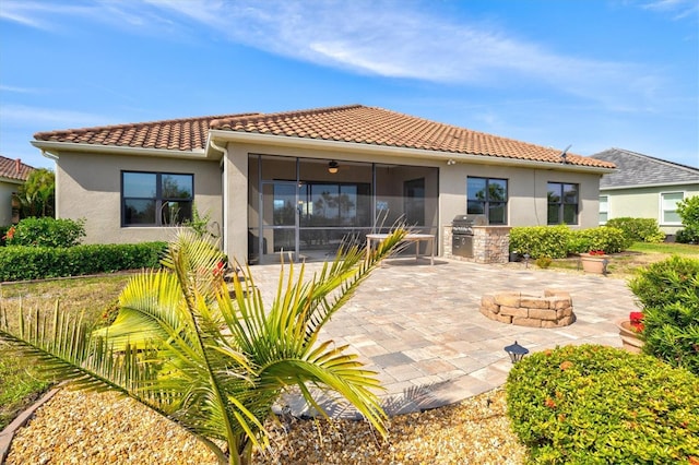 rear view of house with a tile roof, exterior kitchen, a patio area, stucco siding, and a ceiling fan