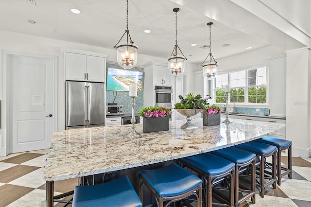 kitchen with light stone counters, a breakfast bar area, high end fridge, and white cabinets