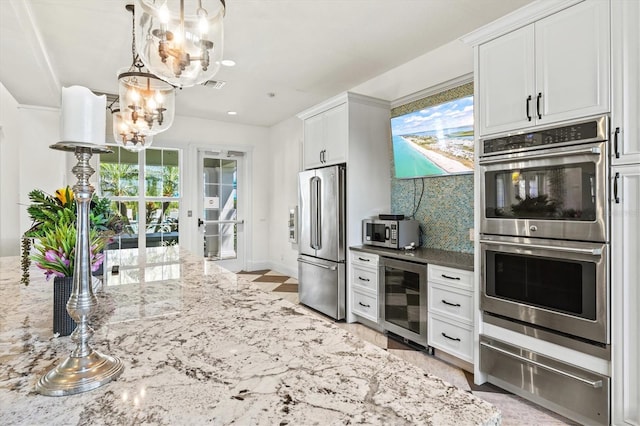 kitchen featuring beverage cooler, stainless steel appliances, an inviting chandelier, a warming drawer, and backsplash