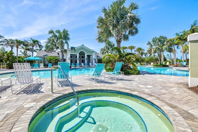 community pool with a patio and a hot tub