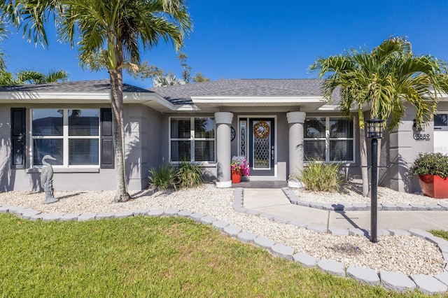 view of front of house with a shingled roof, stucco siding, and a front yard
