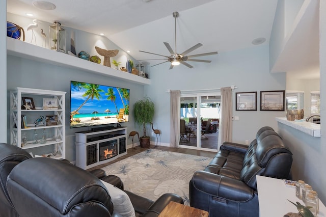 living room with a ceiling fan, a glass covered fireplace, wood finished floors, and high vaulted ceiling