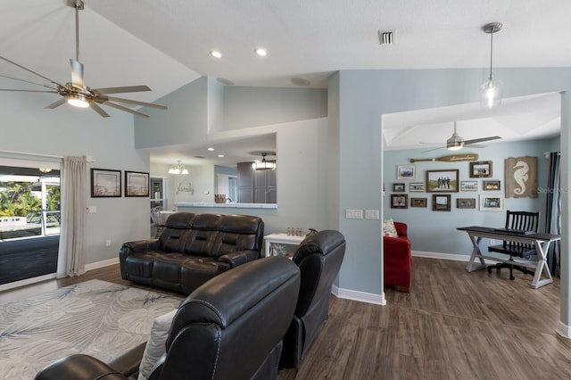 living area with ceiling fan, high vaulted ceiling, baseboards, wood finished floors, and visible vents