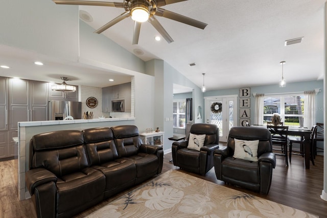 living area with wood finished floors, a ceiling fan, lofted ceiling, and visible vents