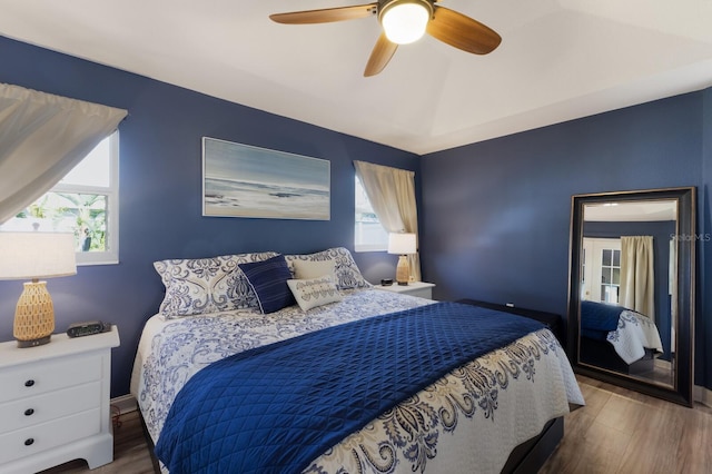 bedroom with a ceiling fan, multiple windows, and wood finished floors
