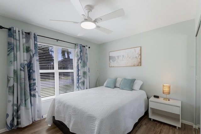 bedroom with baseboards, wood finished floors, and multiple windows