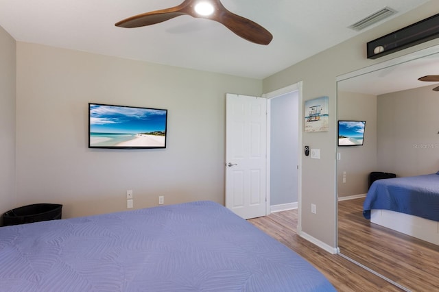 bedroom with visible vents, baseboards, ceiling fan, and wood finished floors