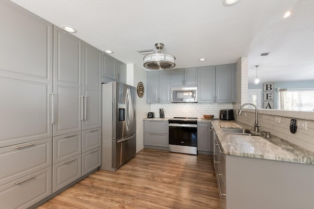3889 Canopy Way, Sarasota, FL 34235 - kitchen featuring stainless steel appliances, gray cabinetry, a sink, backsplash, and light stone countertops