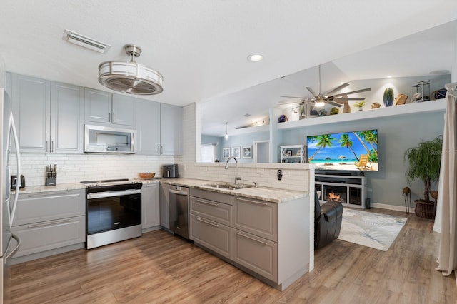3889 Canopy Way, Sarasota, FL 34235 - kitchen featuring appliances with stainless steel finishes, a sink, gray cabinets, a peninsula, and tasteful backsplash