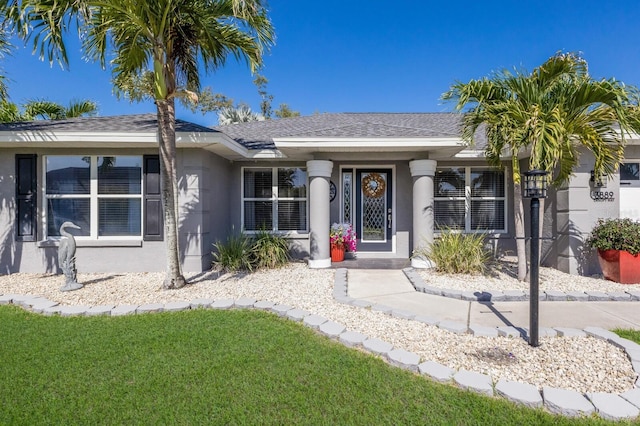 3889 Canopy Way, Sarasota, FL 34235 - property entrance with stucco siding, a yard, and roof with shingles
