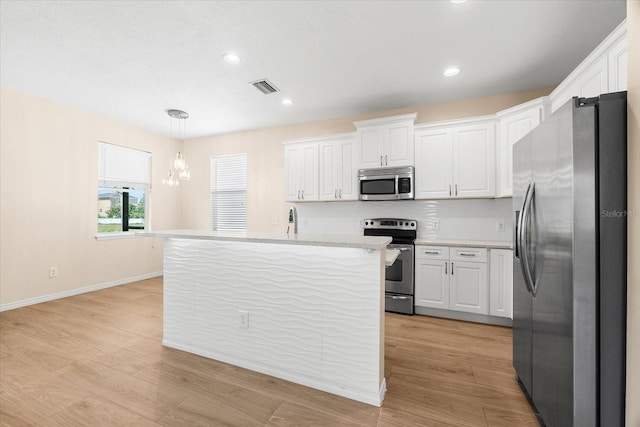 kitchen featuring visible vents, stainless steel appliances, hanging light fixtures, and white cabinets