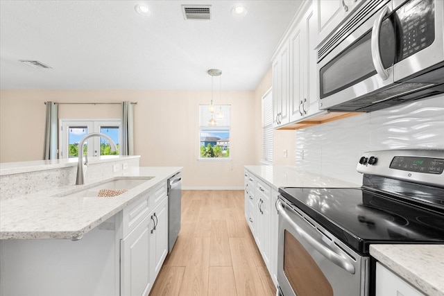 kitchen with a sink, stainless steel appliances, light wood-type flooring, visible vents, and white cabinetry