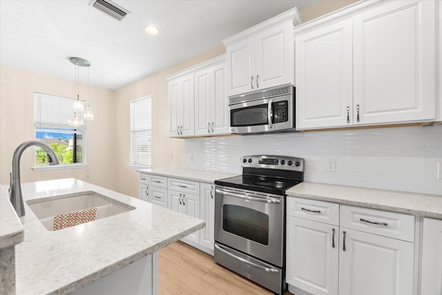 kitchen with light wood finished floors, a sink, stainless steel appliances, visible vents, and white cabinets