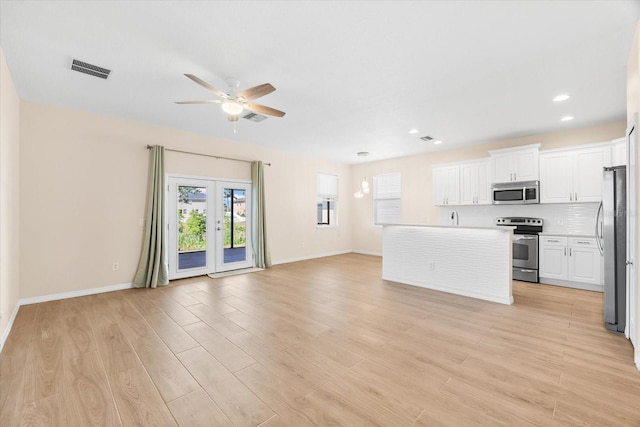kitchen with white cabinets, visible vents, stainless steel appliances, open floor plan, and a ceiling fan
