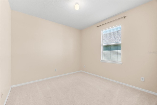 unfurnished room featuring light carpet and baseboards